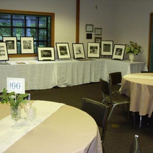 A paint exhibit. Over the tablecloths are white burlap table runners.