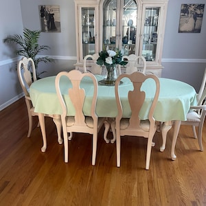 Custom oval table with a mint tablecloth and floral arrangement on the table in a dining room.