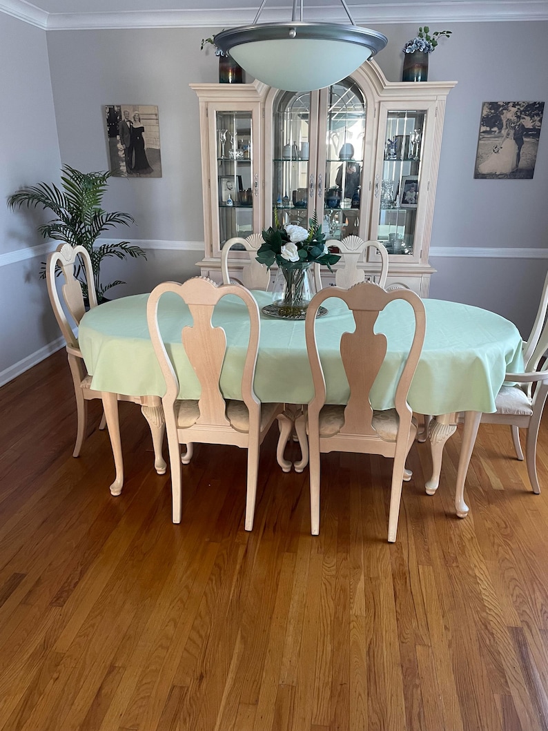 Custom oval table with a mint tablecloth and floral arrangement on the table in a dining room.