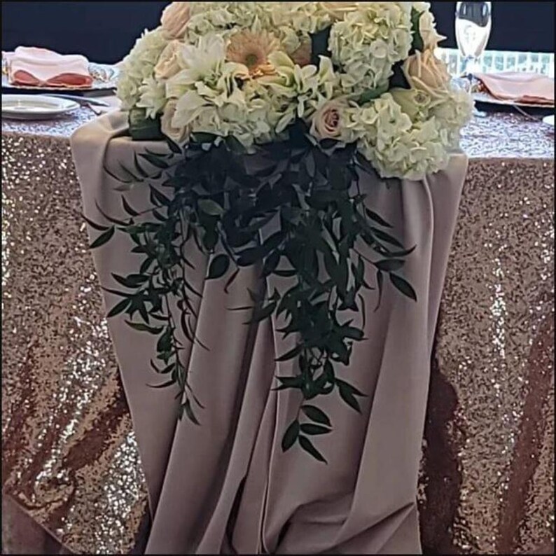 Blush velvet table runner over a sequin tablecloth. Beautiful white flowers on top of the table runner.