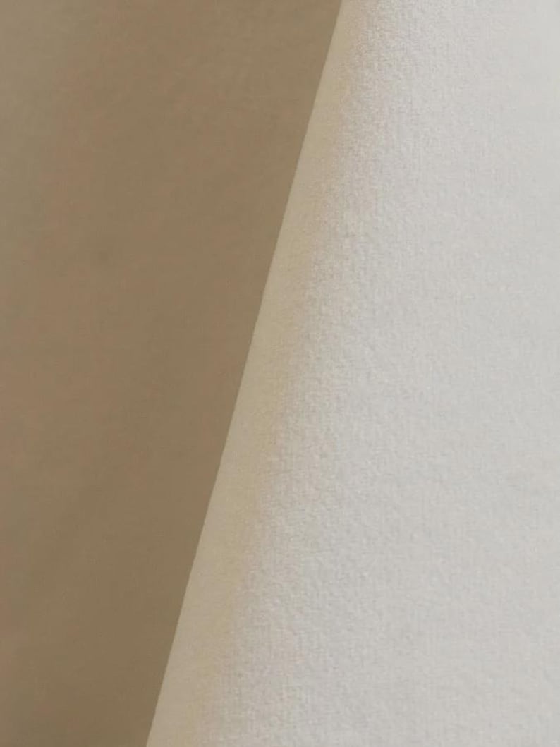 Close-up of a ivory velvet upholstery fabric with a soft, textured surface.
It is 105,000 rub tested which is excellent durable quality manufactured by Premier Table Linens.