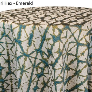 Moss green Shibori tablecloth with a geometric Shibori Hex pattern. The fabric has a textured appearance with a repeating diamond and line design. The tablecloth is draped over a round surface. The tablecloth manufacturer is Premier Linens.