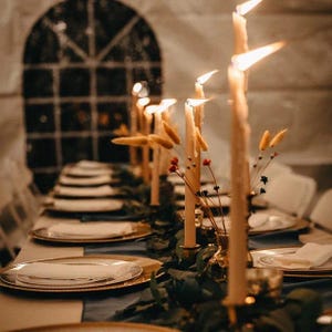 A green velvet table runner drapes over a wooden table set for a dinner party.