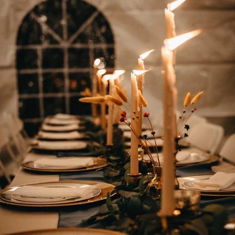 A green velvet table runner drapes over a wooden table set for a dinner party.
