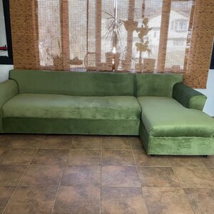 Puede incluir: Un sof&aacute; seccional grande de color verde oliva con una chaise longue en el lado derecho. El sof&aacute; cuenta con una tapicer&iacute;a de tela suave similar al terciopelo, un respaldo largo y apoyabrazos anchos en ambos extremos.
