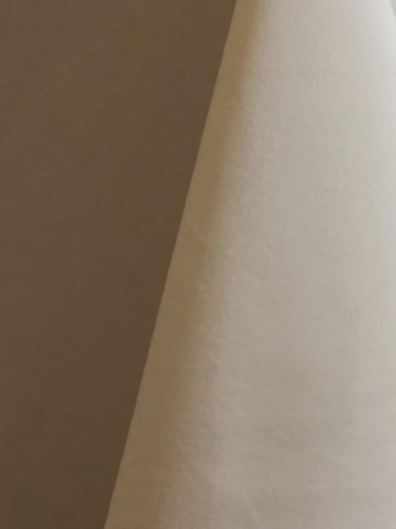 Close-up of a cream velvet upholstery fabric with a soft, textured surface.
It is 105,000 rub tested which is excellent durable quality manufactured by Premier Table Linens.