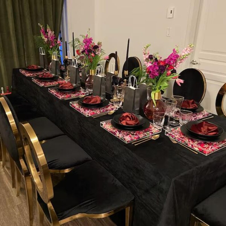 A wedding reception table completely dressed with a black velvet tablecloth, china and decorations.