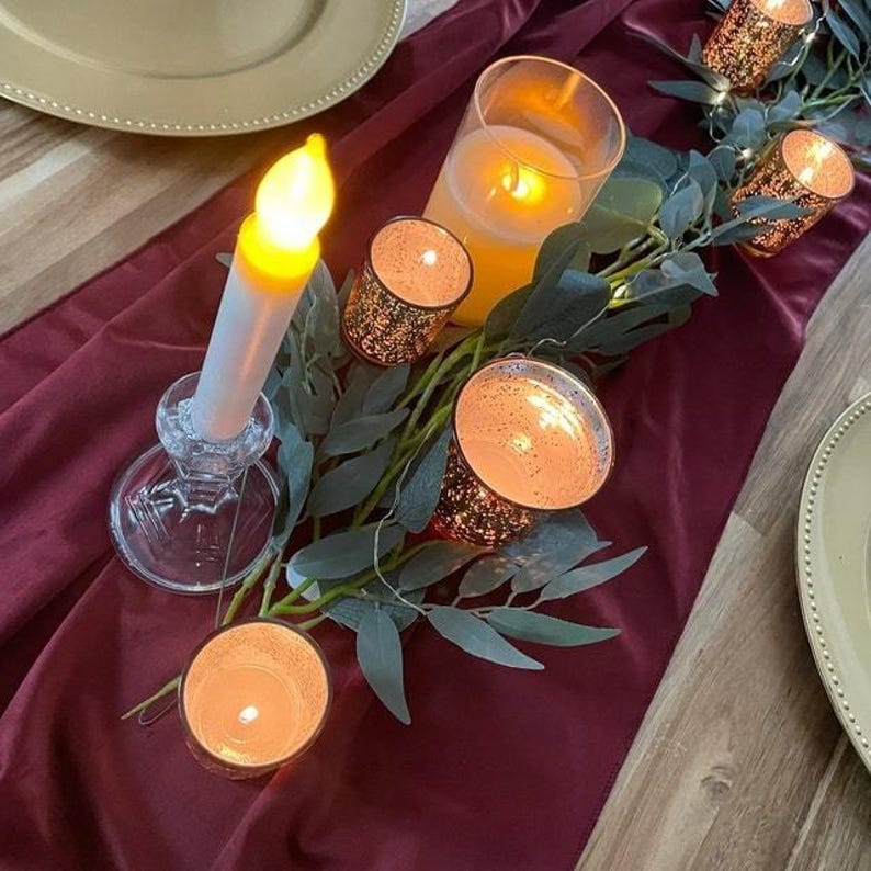A burgundy velvet table runner drapes over a tablecloth set for a formal dinner party.