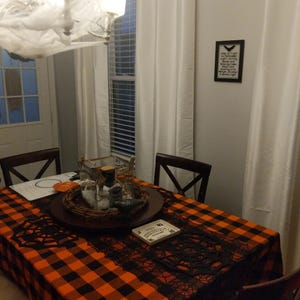 A black and orange checkered tablecloth. This fabric is also called Buffalo plaid tablecloth and is manufactured by Premier Table Linens.