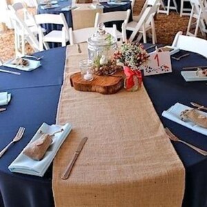 A wedding reception with blue tablecloths and burlap table runners. There are blue cloth napkins on the table.