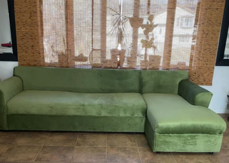 A green sectional sofa with a chaise lounge made with upholstery velvet. The sofa is covered in a soft, plush fabric.