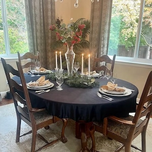 A blue velvet tablecloth with candlesticks in the center of the table. The table is set with white plates and white velvet napkins in the dining room of a home.