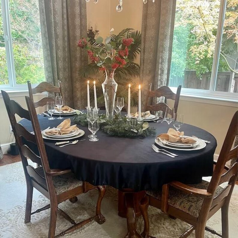 A blue velvet tablecloth with candlesticks in the center of the table. The table is set with white plates and white velvet napkins in the dining room of a home.