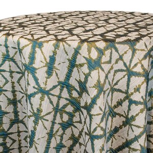 Emerald Shibori tablecloth with a geometric Shibori Hex pattern. The fabric has a textured appearance with a repeating diamond and line design. The tablecloth is draped over a round surface. The tablecloth manufacturer is Premier Linens.