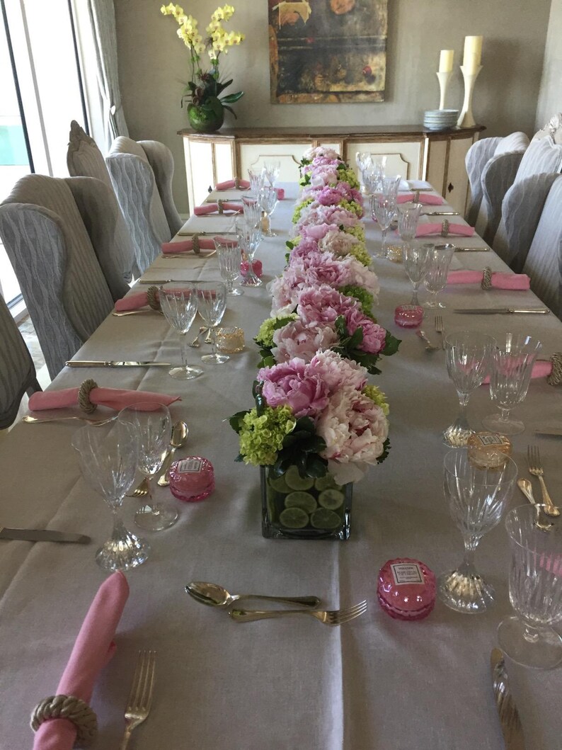 Linen tablecloth and twill cotton napkins on a long rectangular table set for a formal meal.