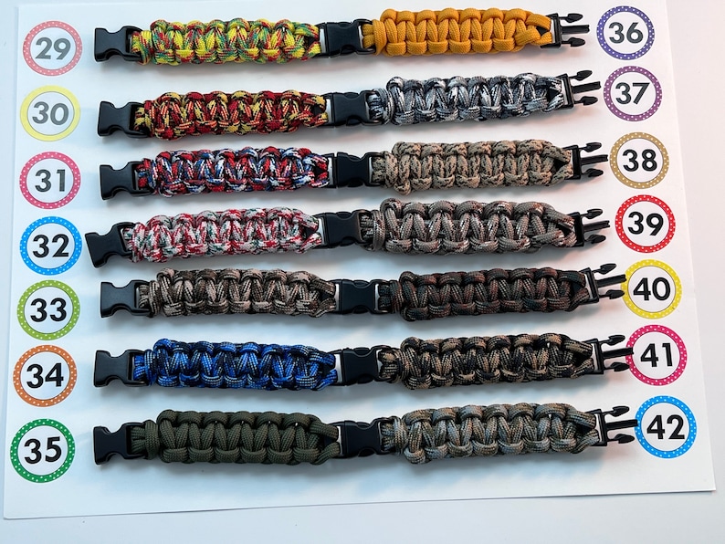 Puede incluir: Un conjunto de diez pulseras de paracord en varios colores y patrones, incluyendo camuflaje, rojo, amarillo y azul. Cada pulsera tiene una hebilla de pl&aacute;stico negro y est&aacute; numerada del 29 al 42.