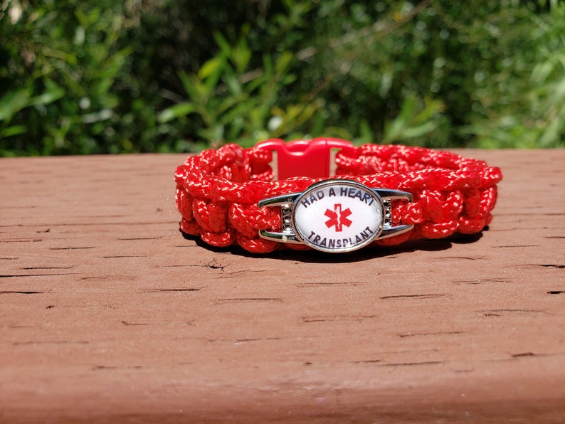 Puede incluir: Pulsera de paracord roja con un dije plateado que dice "Had a Heart Transplant" y tiene un s&iacute;mbolo rojo de estrella de la vida m&eacute;dica.