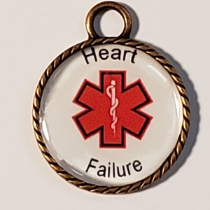 May include: A round, gold-colored metal charm with a white background and a red Star of Life symbol. The text "Heart Failure" is printed in black below the symbol.