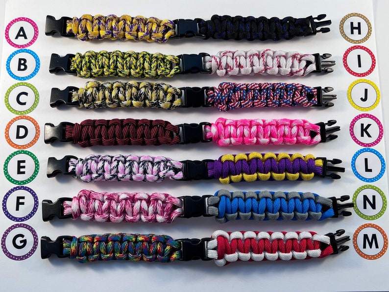 Puede incluir: Diez pulseras de paracord de colores con cierres de pl&aacute;stico negro. Las pulseras est&aacute;n dispuestas en una fila de arriba a abajo, etiquetadas de la A a la G a la izquierda y de la H a la M a la derecha.