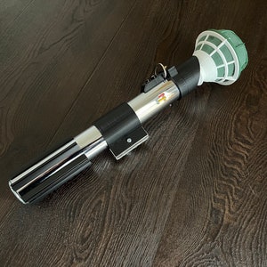 Pu&ograve; includere: Un accessorio per lightsaber nero e argento con una testa in schiuma floreale verde e bianca. Il lightsaber &egrave; fatto di plastica e ha un'impugnatura nera con una lama argentata.
