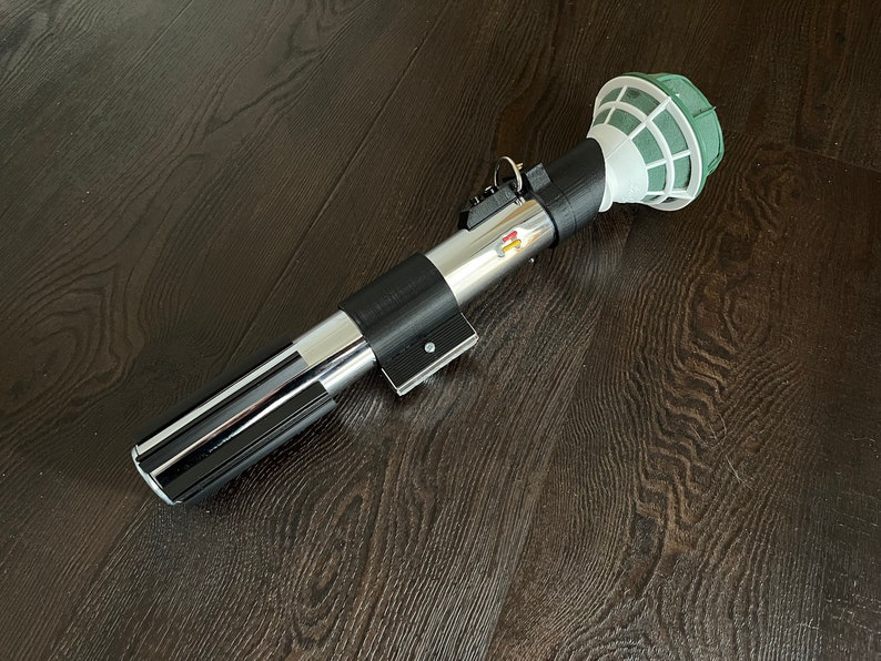 Pu&ograve; includere: Un accessorio per lightsaber nero e argento con una testa in schiuma floreale verde e bianca. Il lightsaber &egrave; fatto di plastica e ha un'impugnatura nera con una lama argentata.