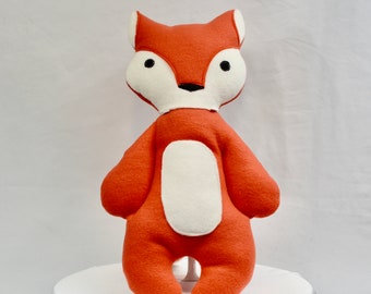 May include: A plush orange fox toy with white accents. The fox has a white belly and a white patch on its face.