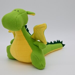 May include: A green and yellow plush dragon toy with a long tail and small wings.
