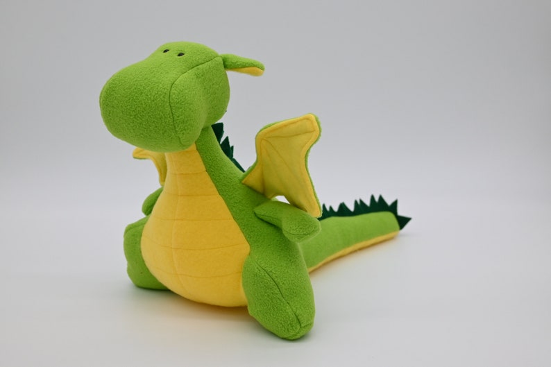 May include: A green and yellow plush dragon toy with a long tail and small wings.