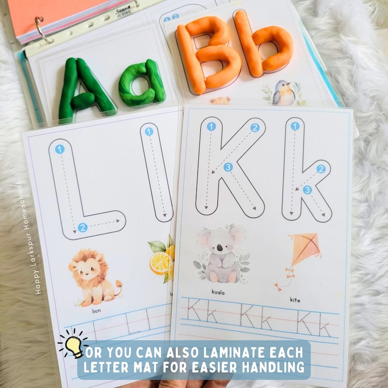 May include: A set of printable alphabet tracing worksheets with dotted lines for kids to practice writing the letters L and K. The worksheets feature illustrations of a lion, koala, and kite. The text "Happy Larkspur Homeschool" is printed on the left side of the page. The text "OR YOU CAN ALSO LAMINATE EACH LETTER MAT FOR EASIER HANDLING" is printed at the bottom of the page.