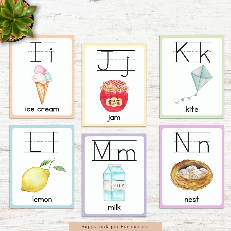 May include: Six colorful flashcards with uppercase and lowercase letters, each featuring a watercolor illustration of an object starting with that letter. The letters are I, J, K, L, M, and N. The objects are ice cream, jam, kite, lemon, milk, and nest.