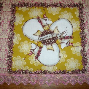 May include: A yellow fabric with a white snowflake pattern and a pink border. Three white polar bears are arranged in a circle around a brown and white object with the text "Merry & Bright".