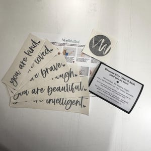 several pieces of paper with inspirational phrases and a small black and white sticker with a logo.