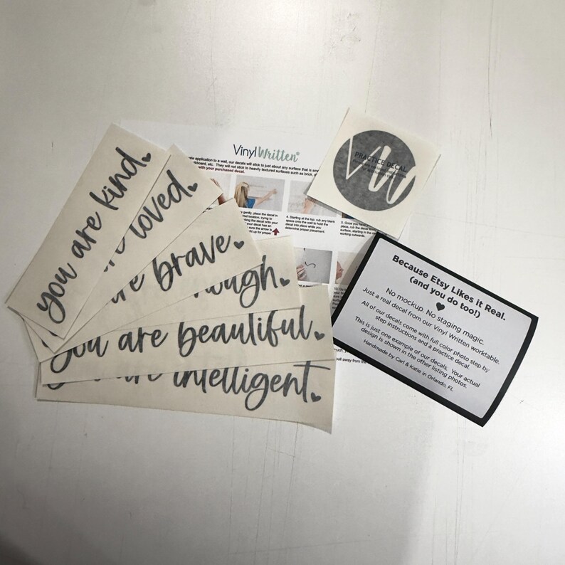 several pieces of paper with inspirational phrases and a small black and white sticker with a logo.