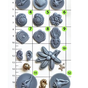 May include: A collection of various sea-themed molds and charms. The molds are gray and circular, featuring seashell, flower, and insect designs. Also included are gold-colored seahorse, turtle, and shell charms. The image is set against a grid background.