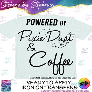 May include: A light blue t-shirt featuring the black text "POWERED BY Pixie Dust & Coffee" with a small star graphic integrated into the design. The image includes additional text stating "READY TO APPLY IRON ON TRANSFERS".