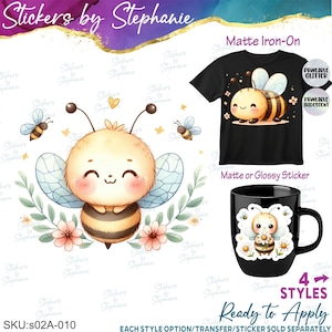 May include: A graphic design featuring a cartoon bee with yellow and black stripes, pink cheeks, and blue wings, surrounded by green leaves and pink flowers. The design is shown applied to a black t-shirt and a black mug, with text labels.