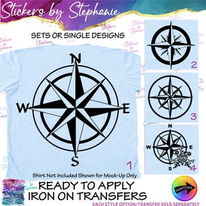 May include: A light blue t-shirt featuring a large black compass rose graphic with cardinal directions N, S, E, W. To the right, three additional black compass designs are displayed, including one with floral accents, labeled with numbers 1, 2, 3, and 4.