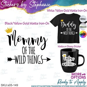 May include: A black t-shirt with white text reading Daddy OF THE WILD THINGS and a yellow crown icon. A black mug features a white sticker reading Custom OF THE WILD THINGS with a crown. Large black text reads Mommy OF THE WILD THINGS.