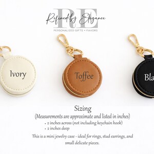May include: Three small, round jewelry cases in ivory, toffee, and black, each with a gold-colored keychain clasp. The ivory case is labeled "Ivory", the toffee case is labeled "Toffee", and the black case is labeled "Black". Each case is approximately 2 inches across and 2 inches deep.