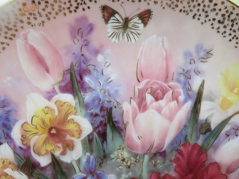K&ouml;nnte beinhalten: Ein antiker Porzellanteller mit einem Blumendesign mit rosa Tulpen, gelben Narzissen, lila Hyazinthen und einem wei&szlig;en Schmetterling.