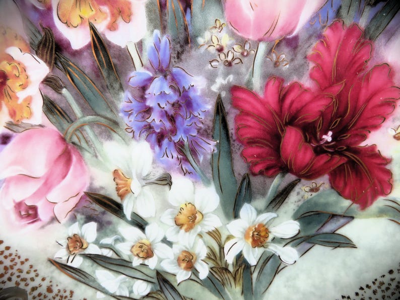 K&ouml;nnte beinhalten: Ein Vintage-Blumendesign mit rosa, roten, wei&szlig;en und violetten Blumen. Die Blumen sind auf einem wei&szlig;en Hintergrund mit goldenen Akzenten gemalt.