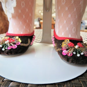 May include: A pair of brown velvet shoes with red trim and colorful beaded embellishments.