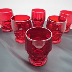 May include: Set of six red glass tumblers with a faceted design. The glasses are clear and have a vintage look.