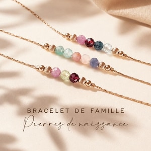 May include: Three delicate gold-toned chain bracelets featuring small, faceted, multi-coloured gemstone beads and round metallic spacers. The text "BRACELET DE FAMILLE Pierres de naissance" is printed in dark brown at the bottom of the image.