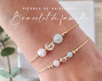 Puede incluir: Dos delicadas pulseras doradas con cuentas de piedras preciosas se muestran en una muñeca. Las pulseras presentan cuentas transparentes, blancas y celeste. El texto "PIERRES DE NAISSANCES" y "Bracelet de famille" es visible.