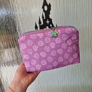 May include: A purple zippered pouch with a white leaf pattern and a rose-shaped zipper pull.