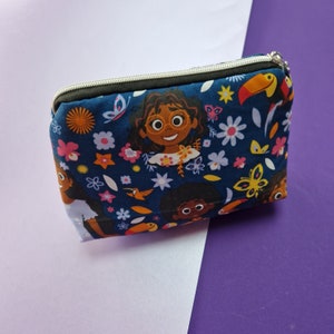 May include: A blue zippered pouch with a colorful print of cartoon girls, flowers, and toucans.