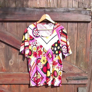 Könnte beinhalten: Ein pinkfarbenes, weißes, gelbes, rotes und schwarzes Kurzarmhemd mit geometrischem und floralem Muster.