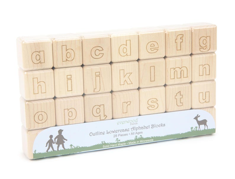 May include: A set of light-colored wooden alphabet blocks featuring engraved lowercase letters from a to u. The blocks are arranged in three rows and held by a light blue paper band labeled Outline Lowercase Alphabet Blocks 28 Pieces.