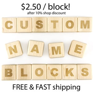 May include: Wooden blocks spelling out "CUSTOM NAME BLOCKS" in all caps. The blocks are light brown and the letters are a darker brown. The text "$2.50 / block! after 10% shop discount" is above the blocks.